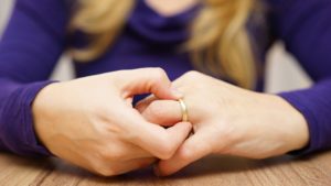 A woman contemplating divorce removes her wedding ring.